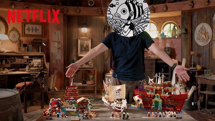 Promotional photo of a masked person arranging One Piece pirate ship models with the Netflix logo